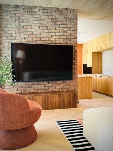 a living room with a large television on a brick wall at Het Huis - luxury villa near Tomorrowland in Willebroek