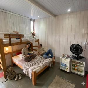 two people sitting on a bed in a bedroom at Estudio Aconchegante no Sul da Ilha in Florianópolis