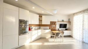 a kitchen with white cabinets and a table with chairs at Marco Polo House in Chioggia