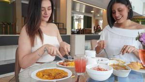 two women eating food at a table with plates of food at Monte Selva Hotel Spa Termal in Baños +12 photos