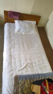 a white bed with white sheets and pillows at Pauro Abashik Hotel in Khagrāchari +1 photo