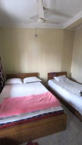 two beds sitting next to each other in a bedroom at Pauro Abashik Hotel in Khagrāchari