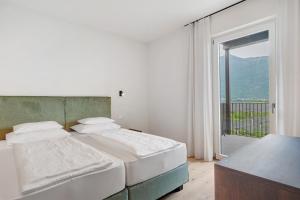 a white bedroom with two beds and a balcony at Gisshübelhof Apartments in Lana +150 photos