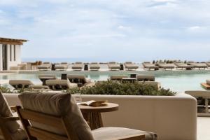 a patio with chairs and a table with the ocean in the background at NĒRO Boutique Hotel in Imerovigli
