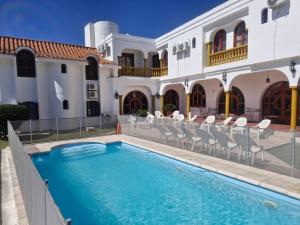 a villa with a swimming pool in front of a building at Hotel Maspalomas in Villa Carlos Paz