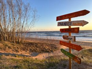 a wooden sign with street signs on the beach at Casa Luba in Saulkrasti +4 photos