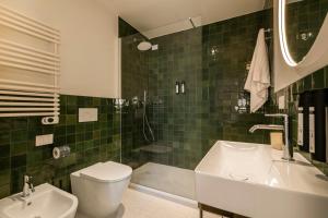 a green tiled bathroom with a toilet and a sink at RELSTAY - Vercelli Suites in Milan