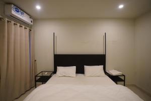 a bedroom with a large white bed with two tables at Oasis Living in Islamabad