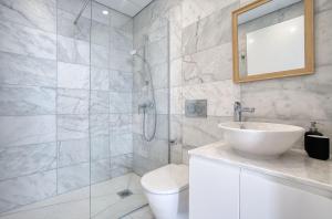a bathroom with a sink and a toilet and a mirror at Modern Sea-View Work Apartment, Sit-Stand Desk, Pool, Gym & Walk to Old Town in Paphos +14 photos