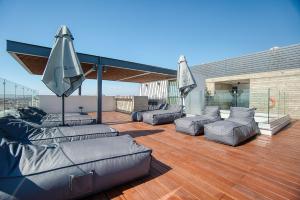 a patio with couches and umbrellas on a deck at Modern Sea-View Work Apartment, Sit-Stand Desk, Pool, Gym & Walk to Old Town in Paphos