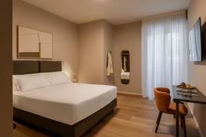 a bedroom with a bed and a desk and a chair at RELSTAY - Vercelli Suites in Milan