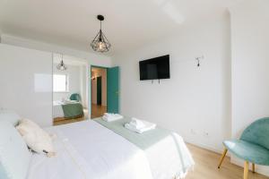 a bedroom with a white bed and a blue chair at BESTVILLAS Âncora Rio in Vila Praia de Âncora