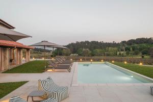 a swimming pool with lounge chairs and an umbrella at Recanto de Passos - Amarante in Amarante