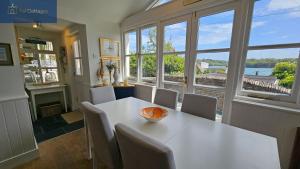 a dining room with a table and some windows at The Summer House in Saint Mawes
