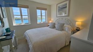 a bedroom with a bed with two pillows and two windows at The Summer House in Saint Mawes