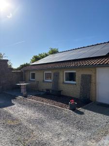 a house with a solar roof and a picnic table at La Vigne à ATH in Ath