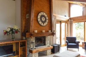 a living room with a fireplace with a clock on the wall at Chalet Au Gré Du Temps in Les Gets