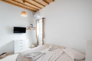 a white bedroom with a bed and a window at White Pearl Mykonos in Mikonos