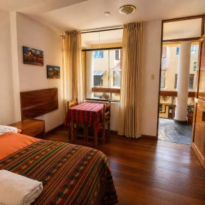 a bedroom with a bed and a table and a window at Killaqente in Cusco