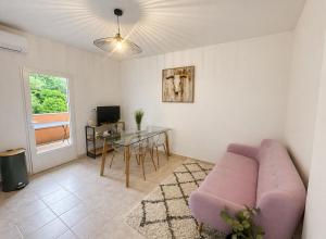 a living room with a pink couch and a table at Charmant 3 pièces avec terrasse, vue mer et parking à Vence in Vence