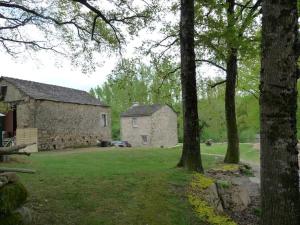 an old stone building with a yard and trees at La Maison du Cros in Cassagnes-Bégonhès