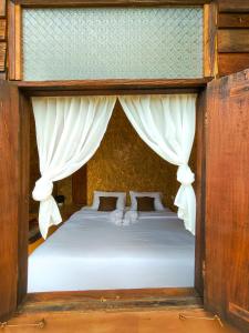 a bedroom with a bed with white curtains at เคียงสะปันโฮม&คาเฟ่ in Ban Huai Ti