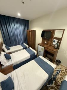 a hotel room with two beds and a desk and a television at فندق العلاء 5 in Ajyad