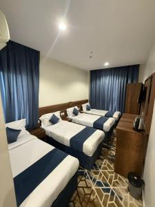 a hotel room with four beds with blue curtains at فندق العلاء 5 in Ajyad