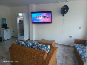 a living room with a couch and a tv on the wall at Hotel Perla Dorada in San Miguel