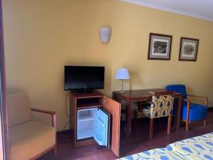 a room with a bed and a desk with a television at Hotel Vado del Duratón in Sepúlveda