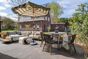 a patio with an umbrella and a table and chairs at Huize Duingeluk in Schoorl