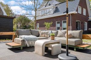 a couch sitting in front of a house with an umbrella at Huize Duingeluk in Schoorl +30 photos