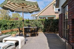 a patio with an umbrella and a table and chairs at Huize Duingeluk in Schoorl
