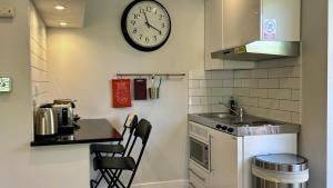a small kitchen with a clock on the wall at THE STUDIO MAIDENHEAD RIVERSIDE in Maidenhead +12 photos