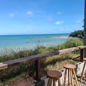 a bench overlooking the ocean with stools at Kitnet Terreo Privada 1 in Conde +5 photos