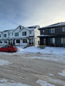 a row of houses with a red car parked in the snow at Haverims Cozy and Neat Basement in Edmonton