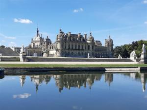 an old castle with its reflection in a body of water at Bienvenue chez Céline in Mareuil-sur-Ourcq