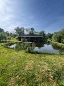 a building in a field next to a pond at Chalet in Fleury-sur-Loire