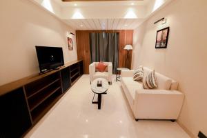 a living room with white furniture and a flat screen tv at Avinash International in Jagdalpur
