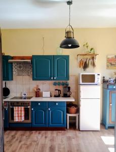 a kitchen with blue cabinets and a white refrigerator at Studniska Country Estate in Studniska