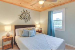 a bedroom with a bed with blue curtains and a window at Sunrise Cottage in Blue Ridge