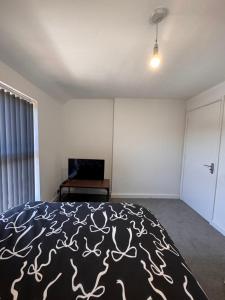 a bedroom with a bed with a black and white blanket at Serenity LTD in Leicester
