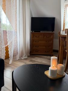a living room with a table with two candles and a tv at Apartament u SKOCZKA in Poronin