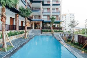 a swimming pool with palm trees in front of a building at Sea Angel Hotel Halong in Ha Long
