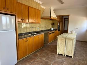 a kitchen with wooden cabinets and a sink and a refrigerator at L'Estança de Can Rodó in Vilobí d'Onyar