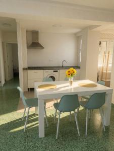 a kitchen with a white table with chairs and flowers at Cullera Beach III in Cullera +14 photos