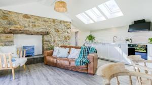 a living room with a couch and a stone wall at Pen Lon Quirt in Newborough
