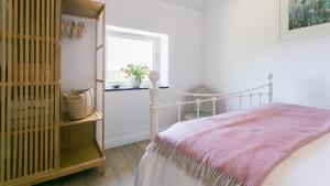 a bedroom with a bed and a window at Pen Lon Quirt in Newborough