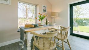 a kitchen with a table with chairs and a window at Pen Lon Quirt in Newborough