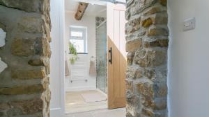 a bathroom with a stone wall and a wooden door at Pen Lon Quirt in Newborough +50 photos